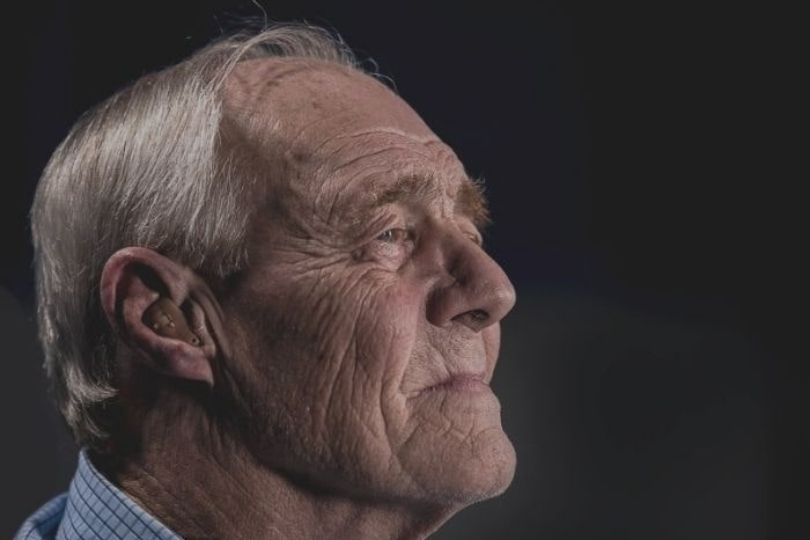 Older gentleman with grey hair and hearing aid
